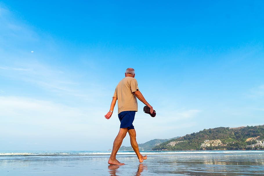 Hombre maduro caminando descalzo en la playa.. México es un país atractivo para los extranjeros jubilados.