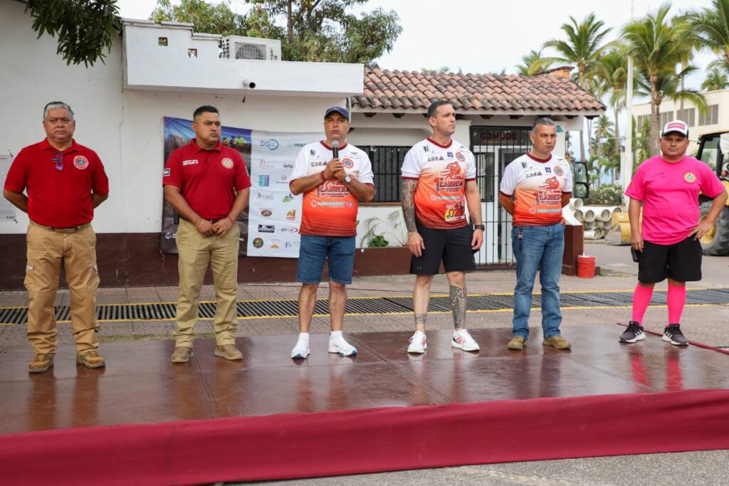 Seis personas, hombres, sobre un estrado, anuncian carrera con causa de protección civil y bomberos de Puerto Vallarta.