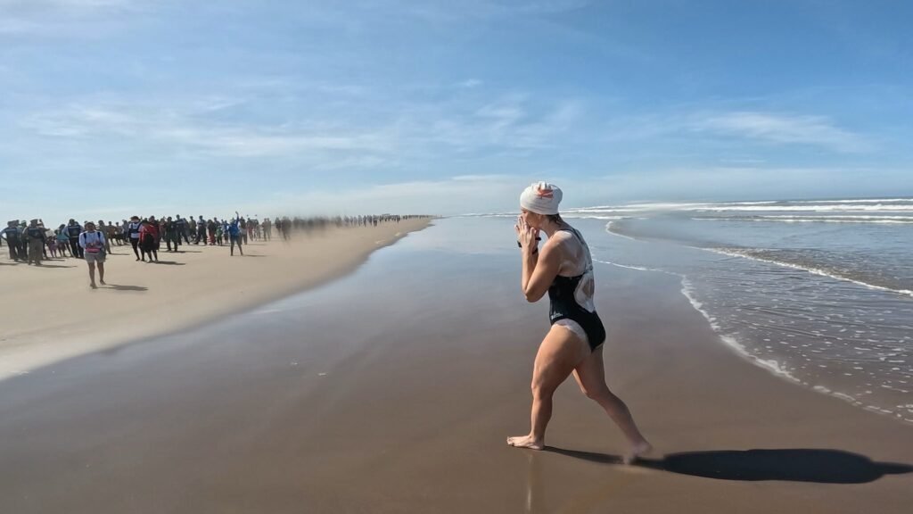 Hazaña histórica: Stephanie Montero cruza 44 km a nado entre dos reservas naturales de Nayarit 1 Una mujer con gorro de nadadora camina por la playa. Stephanie Montero, nadadora-