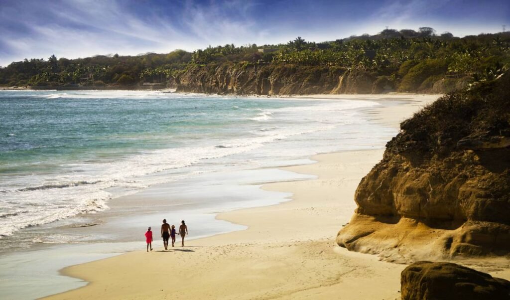 Cuatro personas caminan por la playa Destiladeras en Bahía de Banderas.