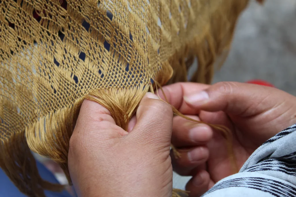 Manos tejiendo un rebozo.