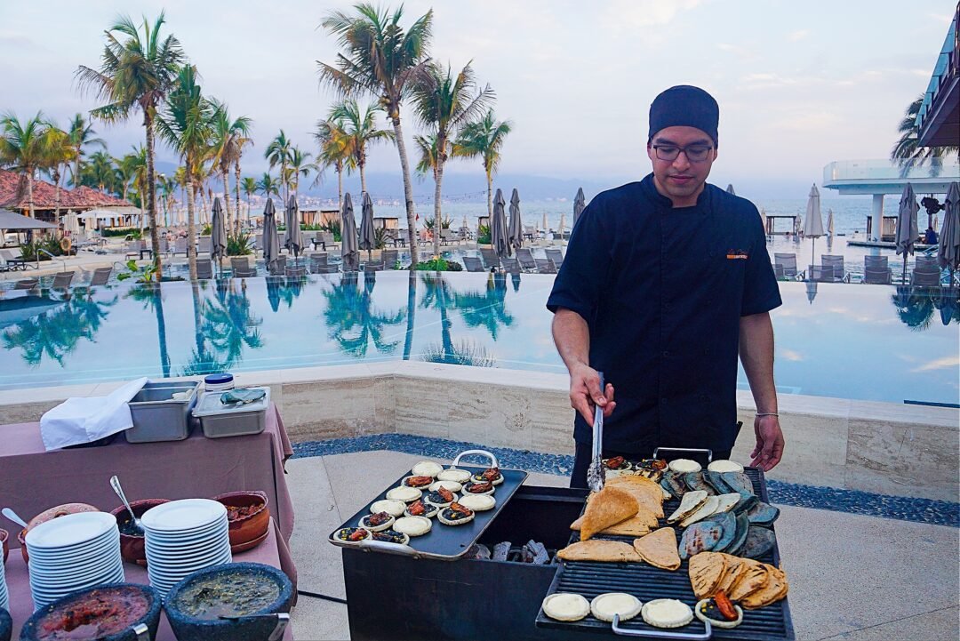 Cocinero a la orilla de la alberca en el Food Market del Vallarta Invitational 2026.
