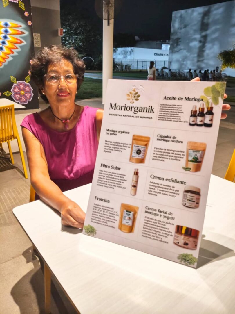 Mujer muestra un cartel que dice Moriorganik, como parte del programa Sedecam para adultos mayores.
